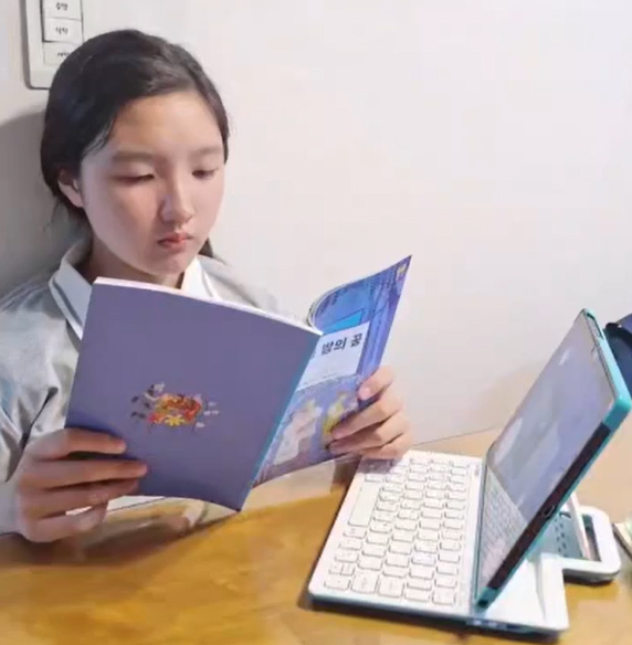 책을 펼쳐 화상수업을 듣는 아이