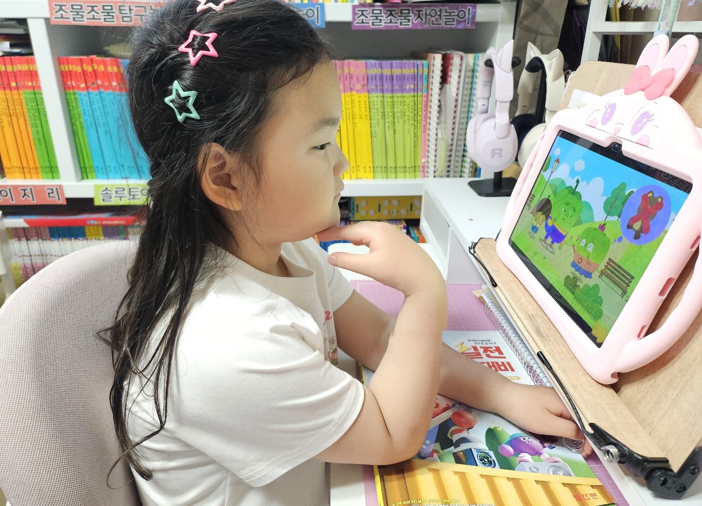 책장 앞에서 태블릿 학습을 하는 아이